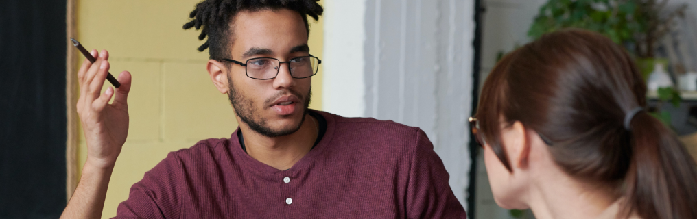 Man in glasses talking to woman.