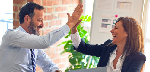 Man and women in office attire high-fiving