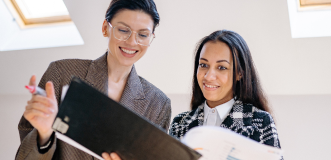 One woman showing another woman her notebook